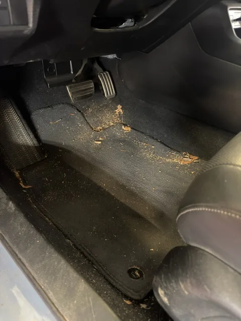 Car floor and pedals before detailing — covered in dirt and debris
